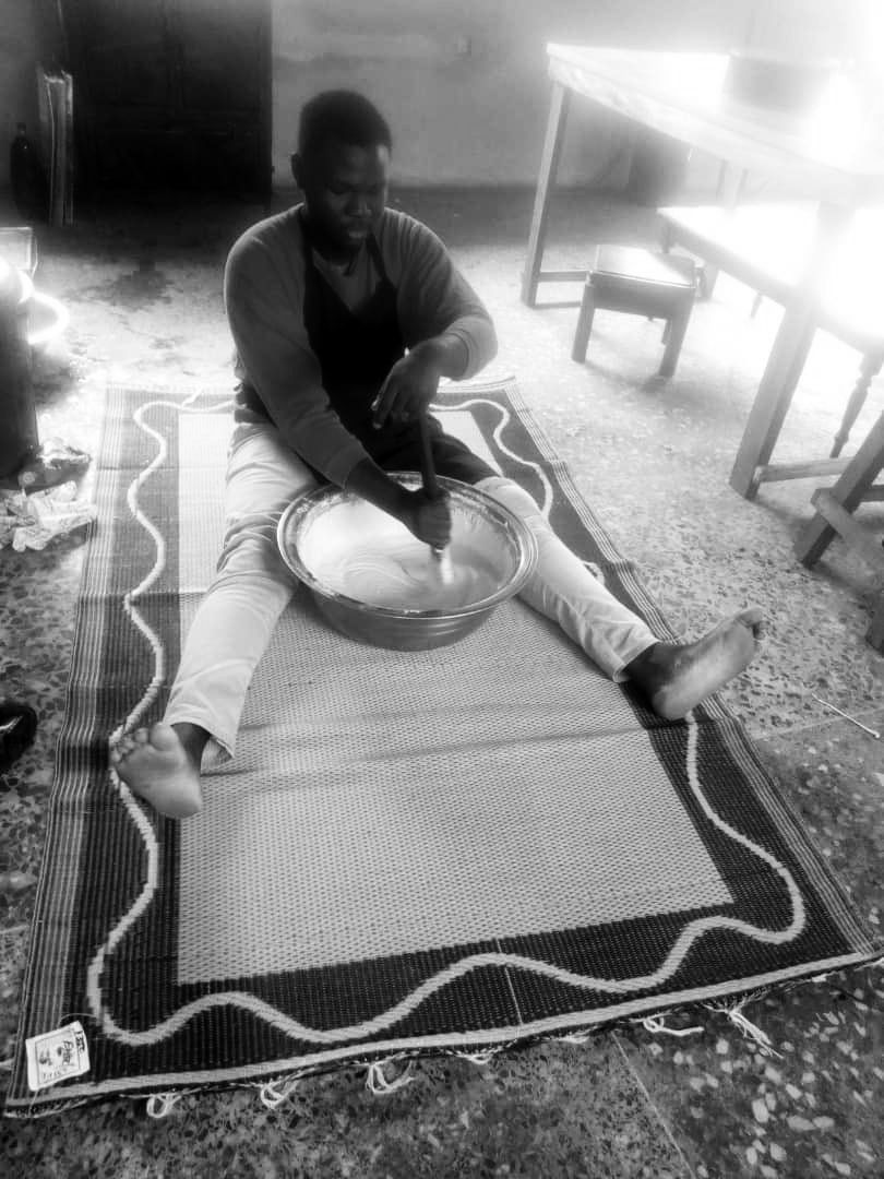 Harold in 2020, sitting on a woven mat mixing dough in a large bowl